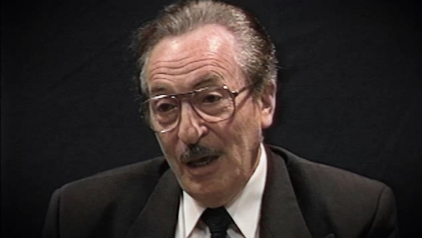 Capture d'écran du témoignage vidéo du survivant de l’Holocauste Michael Kutz, assis devant un fond noir, et regardant à la gauche de la caméra. Son visage et ses épaules sont visibles à la caméra.